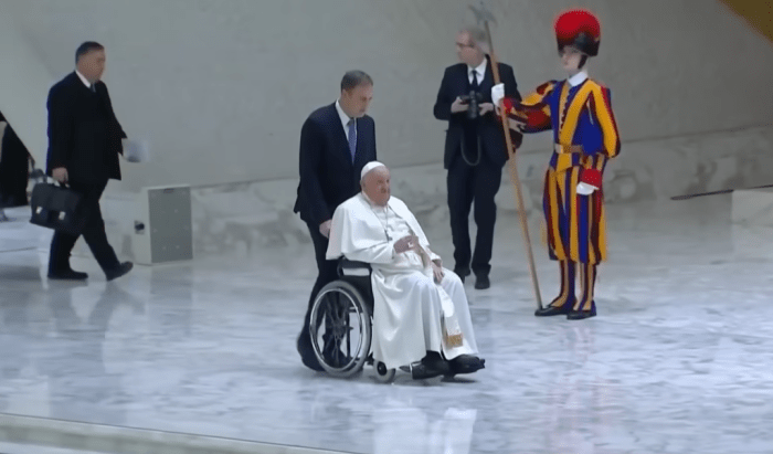 Pope Francis in a wheelchair being pushed, Photo Credit: Today