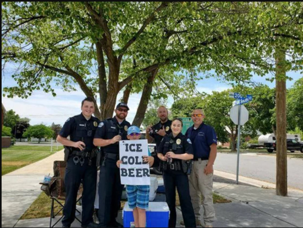 Seth Parker posing with police officers for a photo with his infamous "ice cold beer" sign, Photo Credit: Brigham City Police Department/Facebook