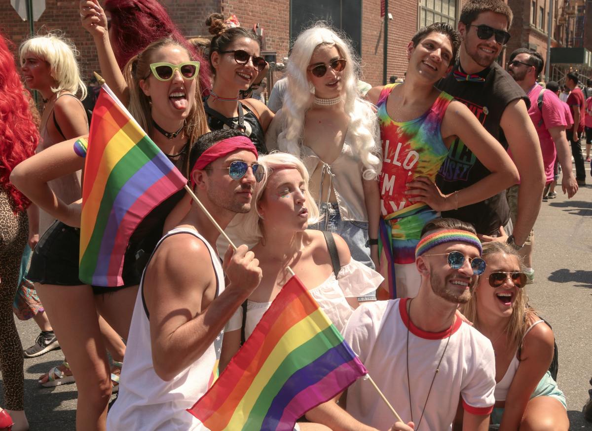 People posing for a photo on the street with rainbow flags, Photo Credit: Pexels