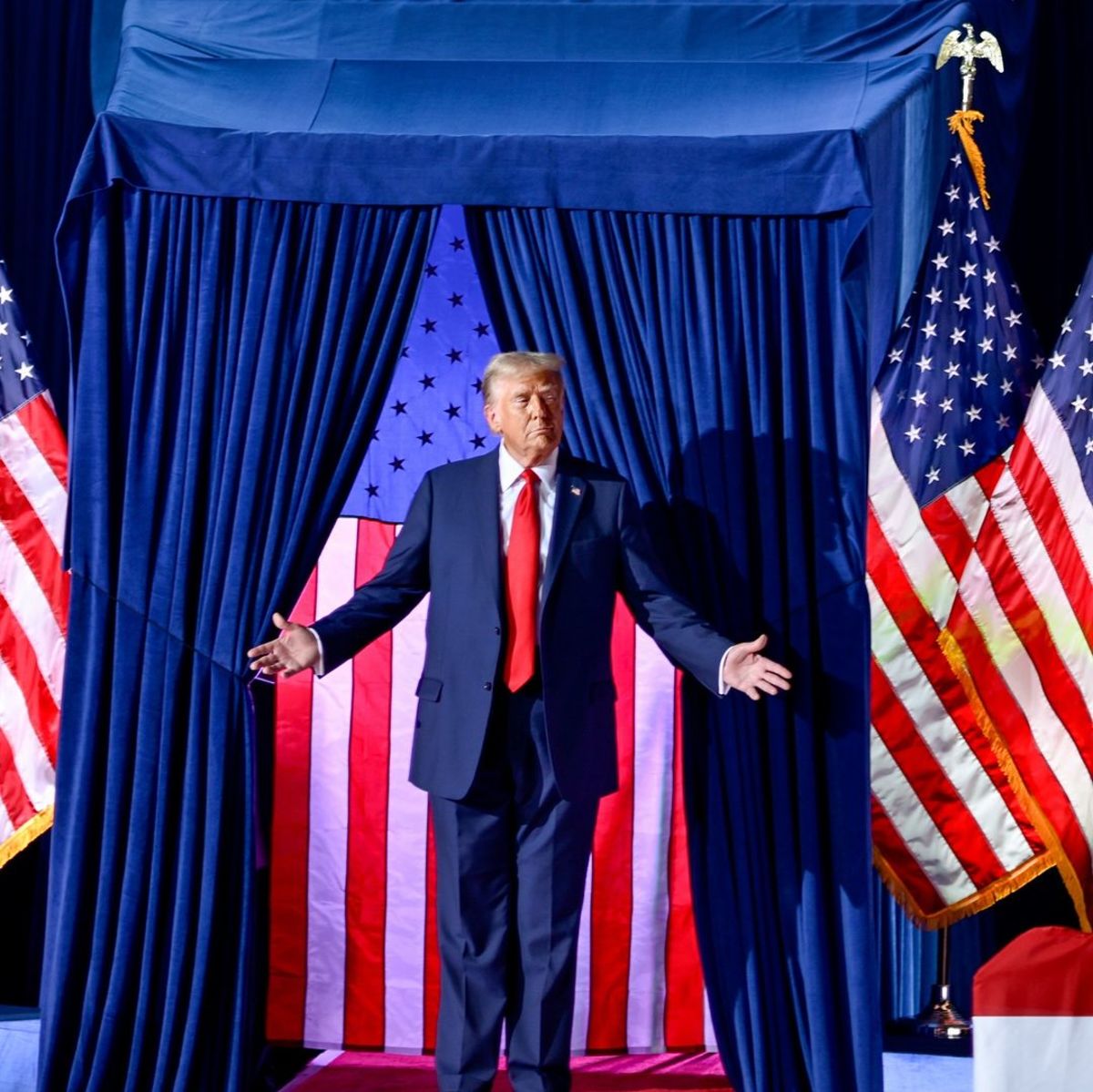 Donald Trump standing on a stage with US Flag behind, Photo Credit: realdonaldtrump/Instagram