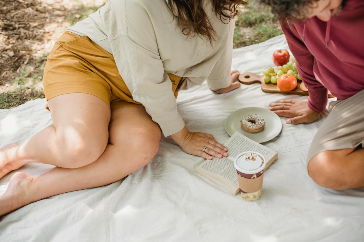 Man and woman sitting on a picnic blanket (for illustrative purposes), Photo Credit: Pexels