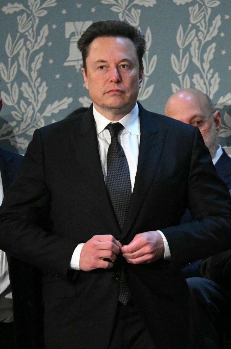 Elon Musk buttoning his coat, Photo Credit: Elon Musk/X