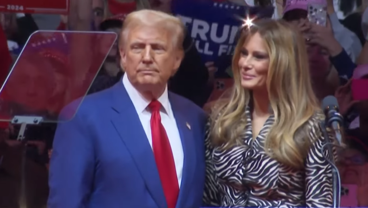 Trump standing with his wife at a rally, Photo Credit: Times Of India/Youtube