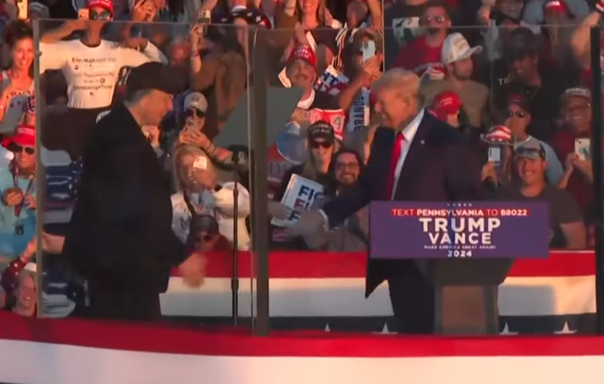 Elon Musk and Trump shaking hands on stage at a rally, Photo Credit: Times Of India/Youtube