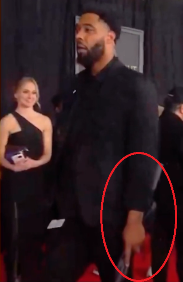 Miley Cyrus' bodyguard walking on the GRAMMYs' red carpet holding an umbrella, Photo Credit: alienthemartian/youtube